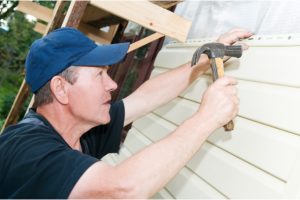 Siding Repairs by worker with a hammer